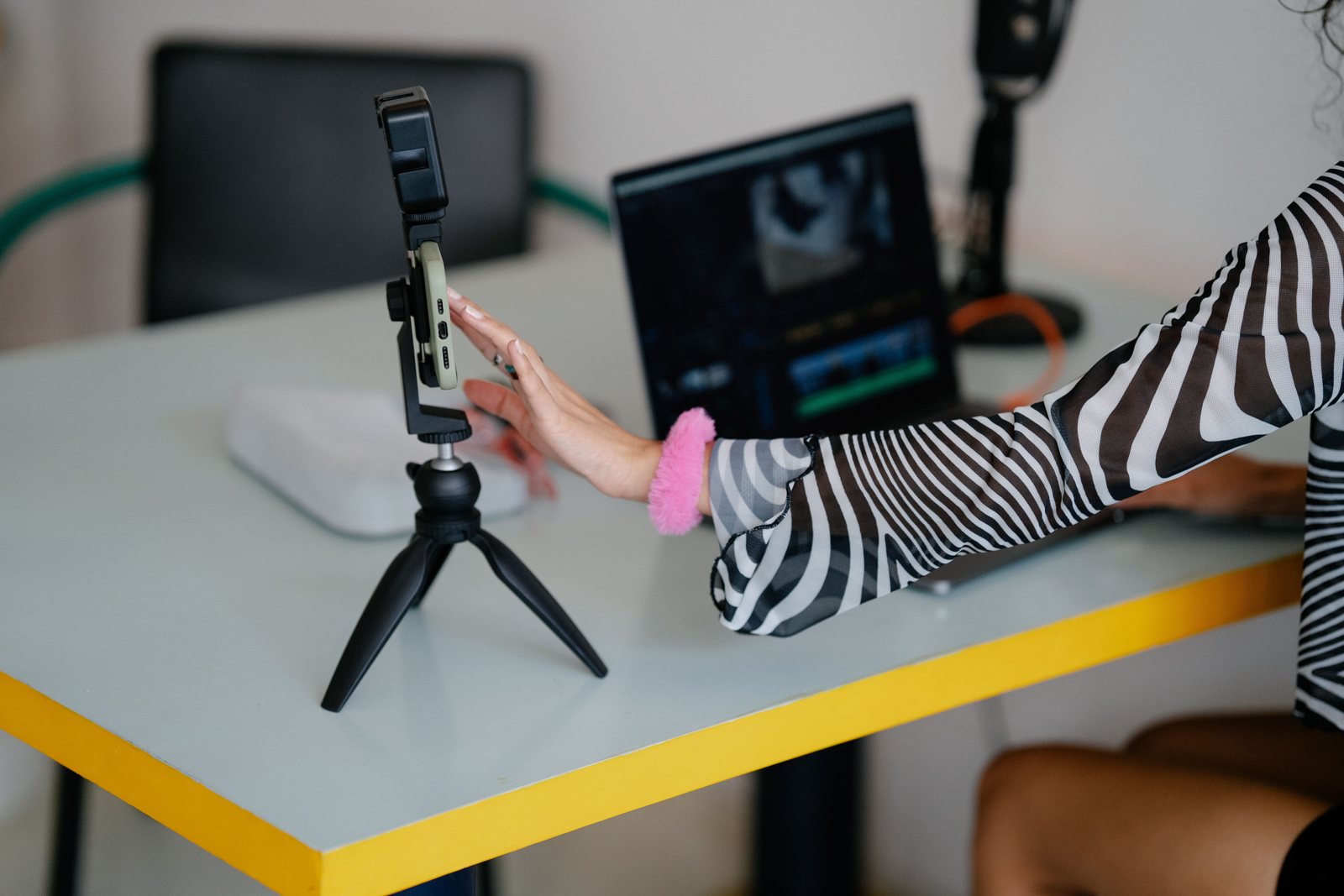 Smartphone on a tripod next to a laptop editing a video